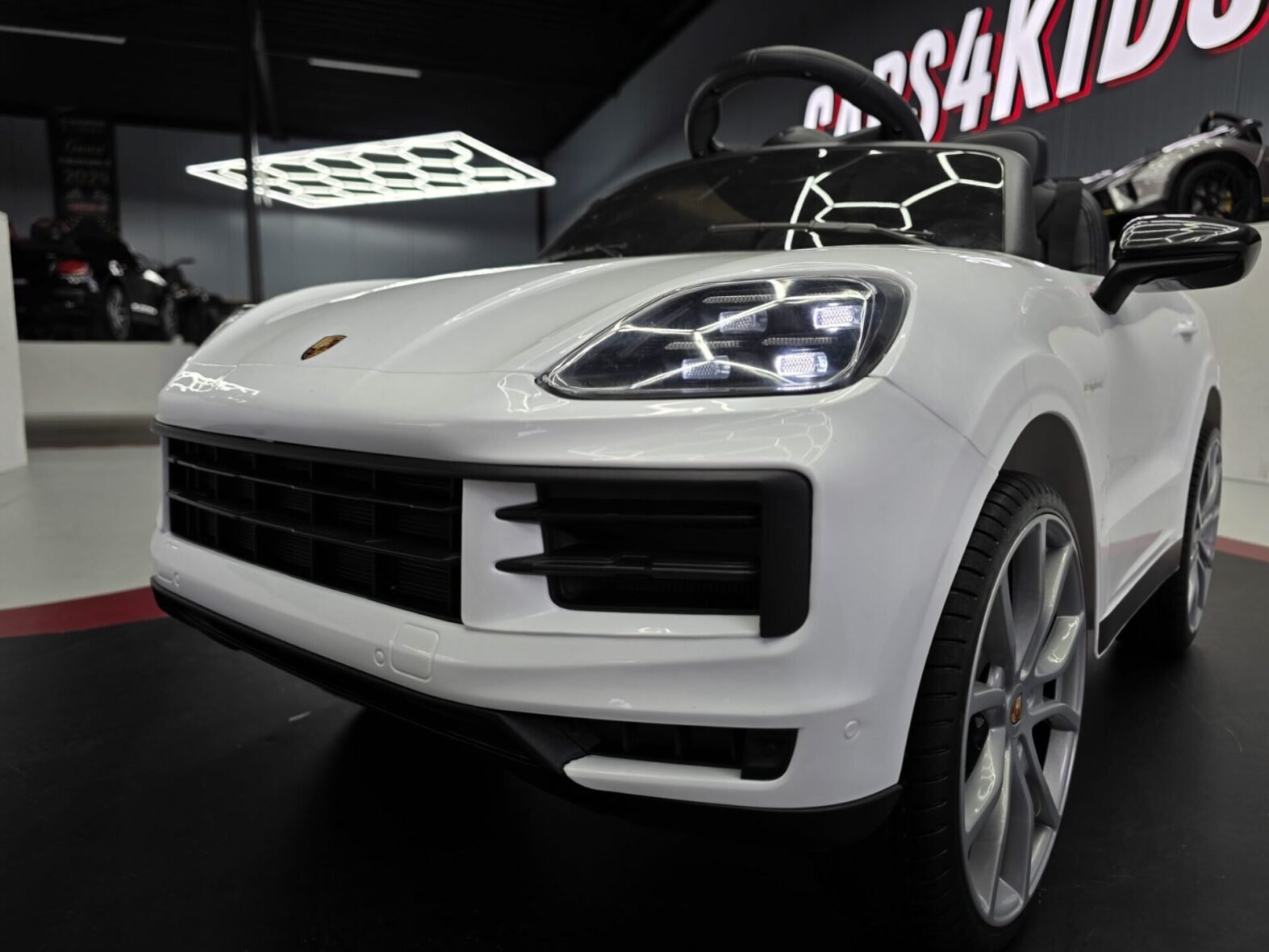 Child driving white Porsche Cayenne electric ride-on car