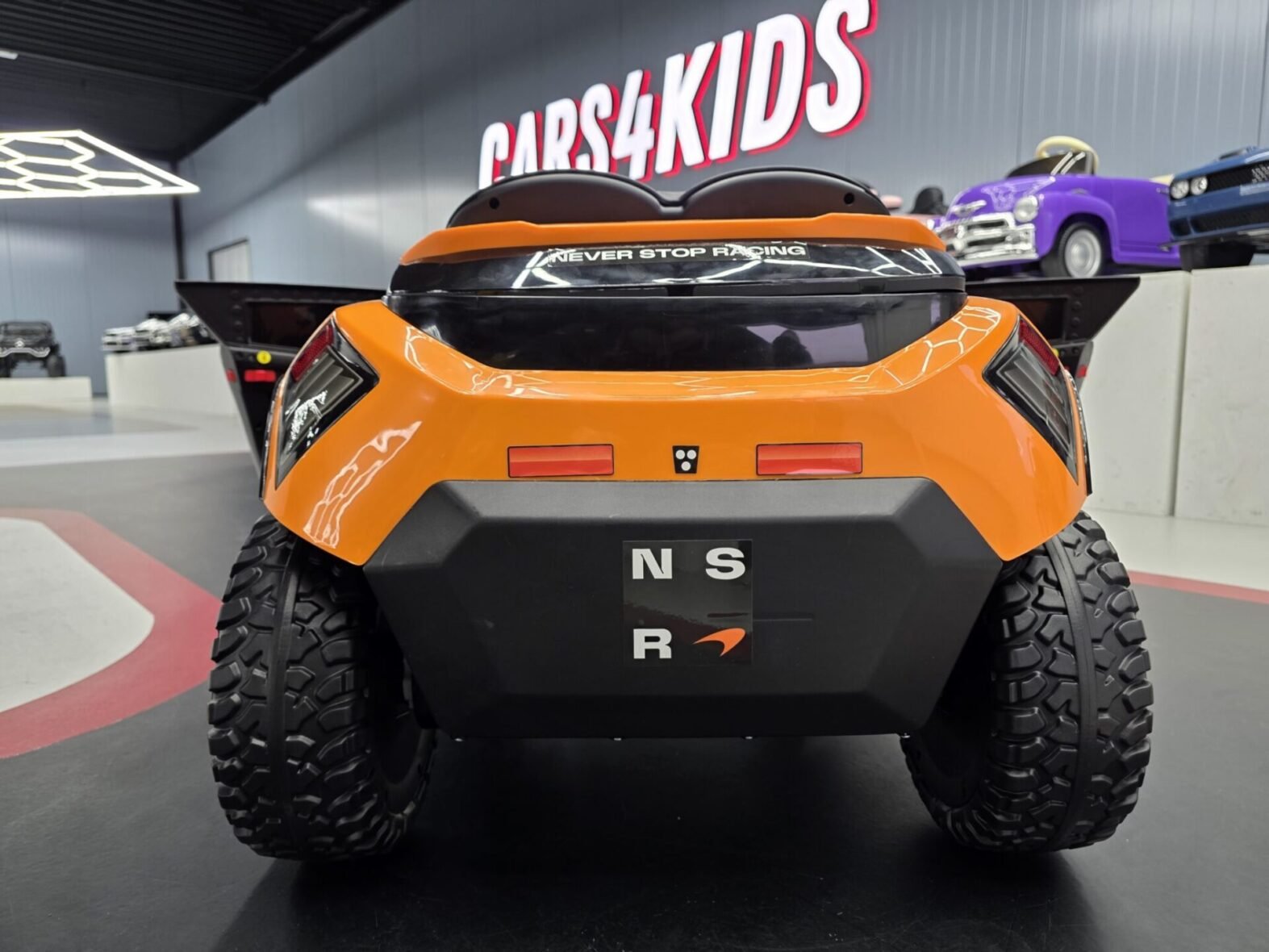 Child driving orange McLaren Rally electric ride-on car